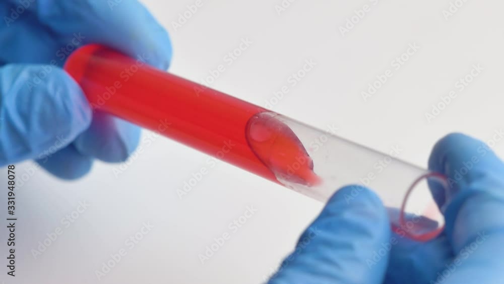 Hand in gloves holds a test tube with red liquid. Hand in gloves holds a test tube with red liquid.