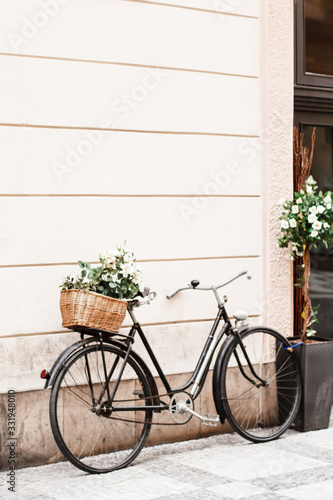 a retro Bicycle stands against the wall with a basket of flowers