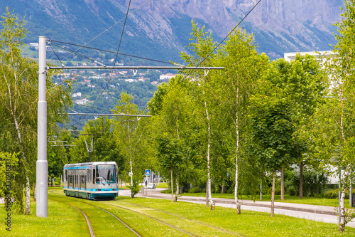 Modern tram on the streets of Grenoble city. In 1987, Grenoble became the second French city to reintroduce tramways. French Alps on background photo