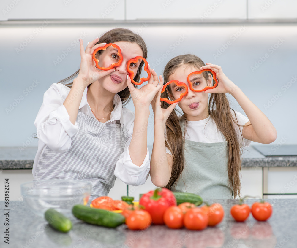 Mother and child preparing healthy food and having fun, holds a pepper in front of their eyes like a glasses Mother and child preparing healthy food and having fun, holds a pepper in front of their eyes like a glasses