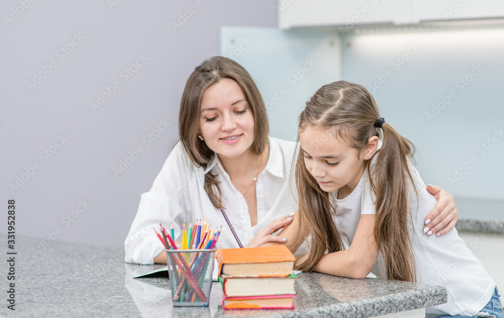 Happy family at home. Mother and her daughter doing homework together. Empty space for text Happy family at home. Mother and her daughter doing homework together. Empty space for text