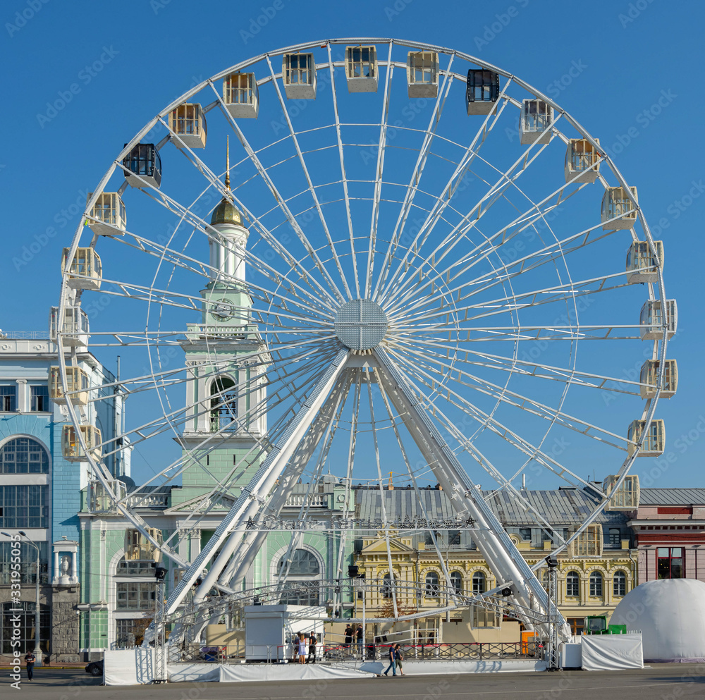Ferris wheel on a town square on a sunny day against bright blue sky