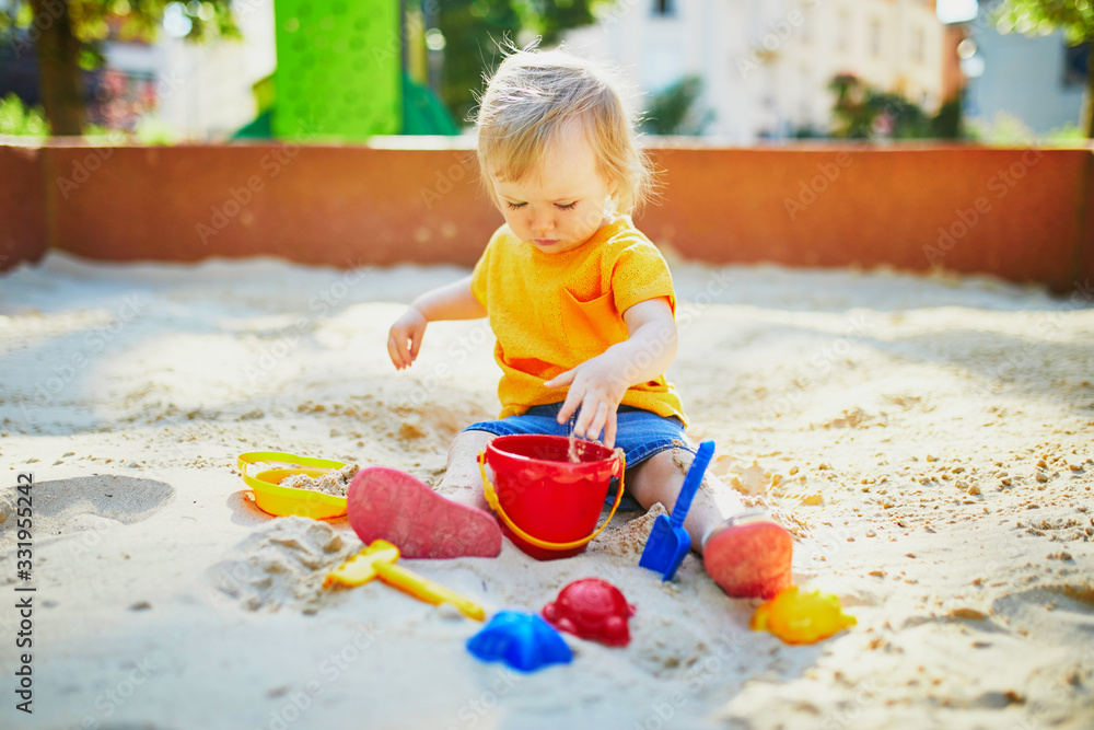 Adorable little girl having fun on playground in sandpit Adorable little girl having fun on playground in sandpit