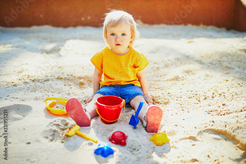 Obraz na plátně Adorable little girl having fun on playground in sandpit