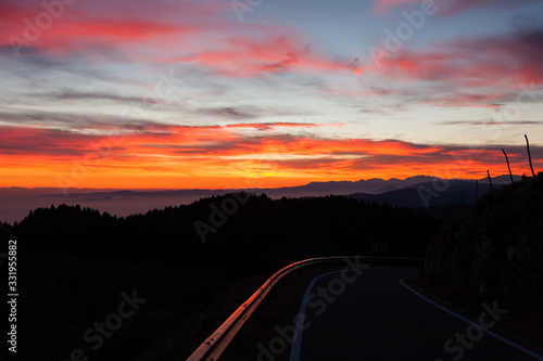 Dramatic red sky with reflections on guard rail road