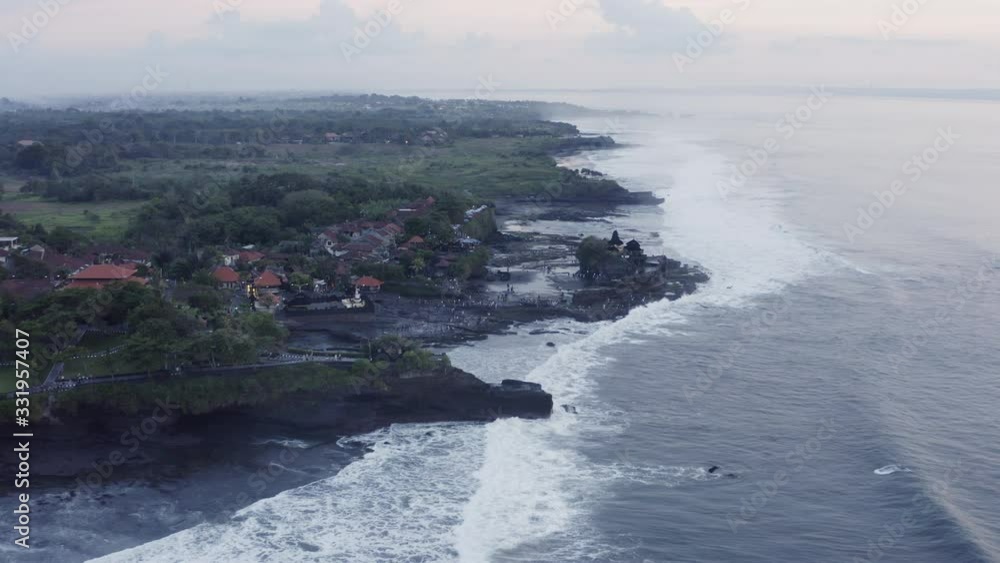 Tanah Lot temple complex located on the offshore Rock with huge tidal waves crushing on shore on the sunset. Bali, Indonesia, Open aerial shot Tanah Lot temple complex located on the offshore Rock with huge tidal waves crushing on shore on the sunset. Bali, Indonesia, Open aerial shot