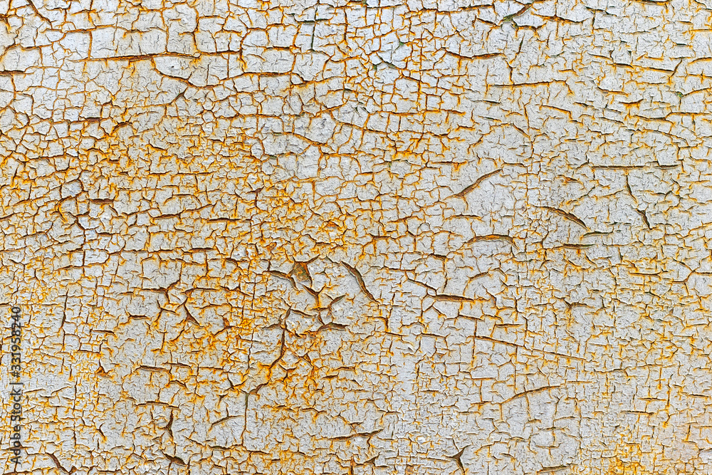 Old white paint is peeled and crumbled from a rusty metal plate.