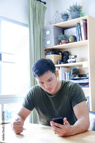 young asian wearing a green tshirt working with laptop in home office