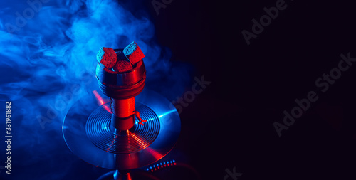 red hot shisha coals in a metal hookah bowl against a background of smoke