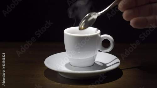 Steam rises from a cup of hot coffee. Black background