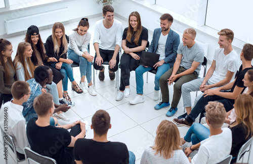 large group of diverse young people sitting in a circle © ASDF