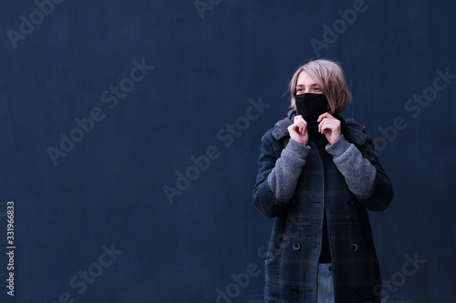 COVID-19 Pandemic Coronavirus A young woman on a black backgound in a protective mask for the spread of the SARS-CoV-2 disease virus. Girl with a black mask on her face against coronavirus disease