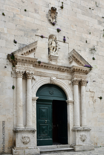 The flowers growing luxuriantly over the main entrance to church in Old Omis city, Dalmatia, Croatia © gadzius