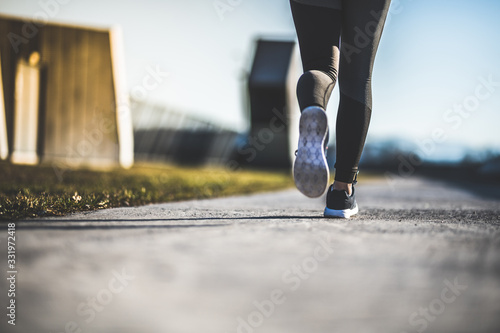 Close up of women's legs running on asphalt road