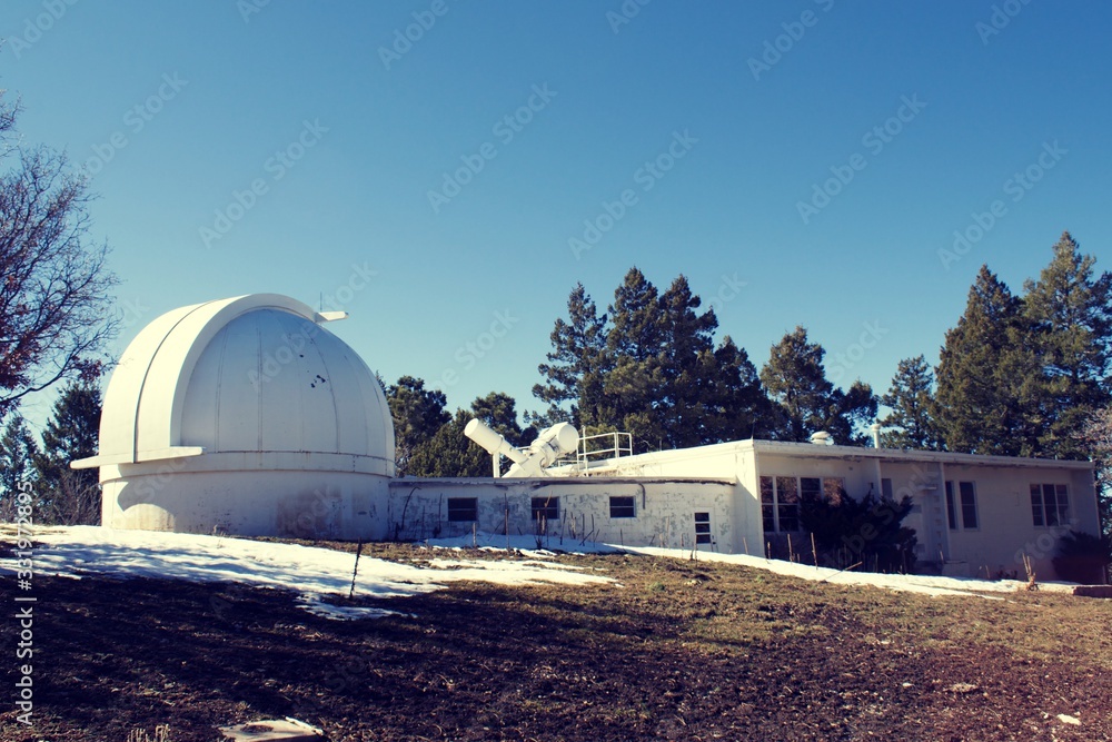 Dome telescope at observatory, with pine trees and snow with clear blue sky Dome telescope at observatory, with pine trees and snow with clear blue sky