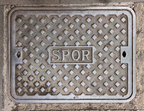 Photography Rome, Italy - Characteristic iron manhole cover in the streets of the city of Rome, with the inscription SPQR (Senatus Populusque Romanus, The Roman Senate and People)