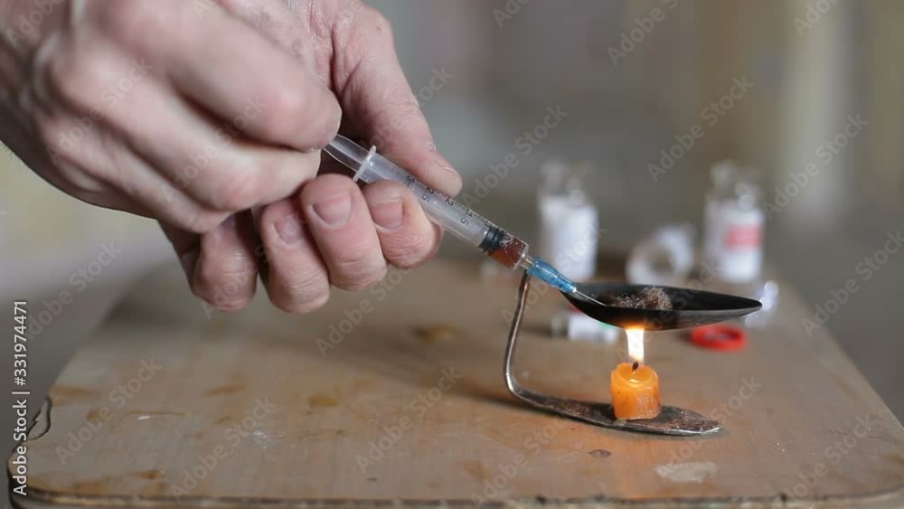 A drug addict draws a drug into a syringe and releases air from it. A male addict prepares to make an injection. A drug addict draws a drug into a syringe and releases air from it. A male addict prepares to make an injection.