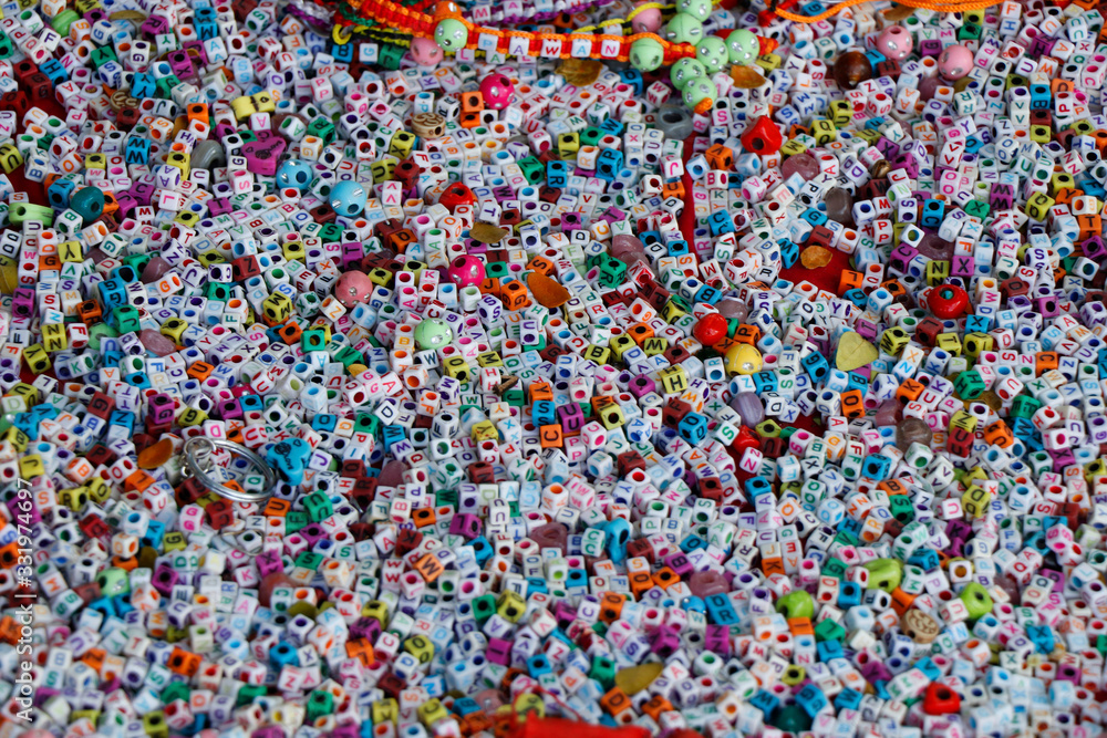 colorful beads for weaving bracelets. Many acrylic cube shape alphabet letter beads. Concept of needlework.