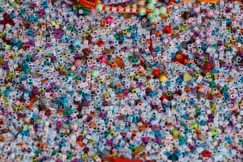 Fototapeta premium colorful beads for weaving bracelets. Many acrylic cube shape alphabet letter beads. Concept of needlework.