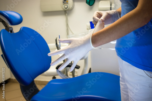 Nurse at doctor taking on new sterile gloves 