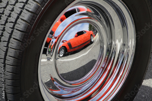  red car is reflected in the wheel of another car © Paul