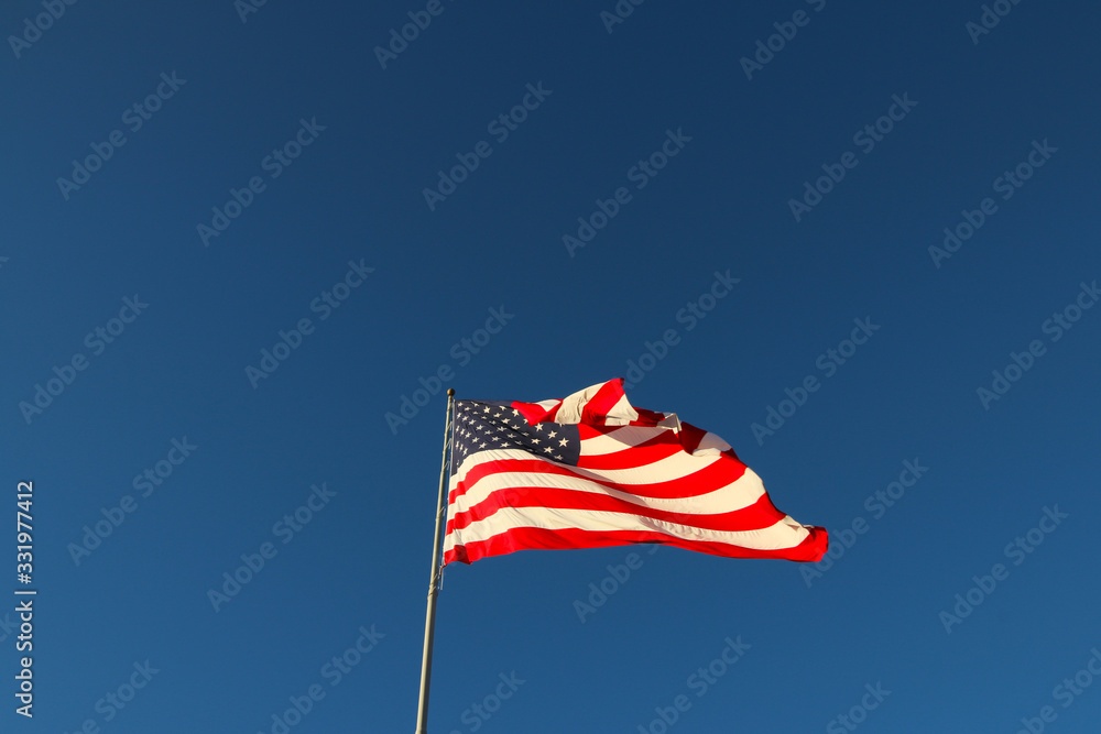 Fototapeta premium American flag waving in the wind with blue sky background
