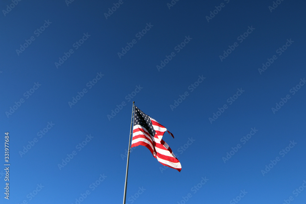 American flag waving in the wind with blue sky background American flag waving in the wind with blue sky background