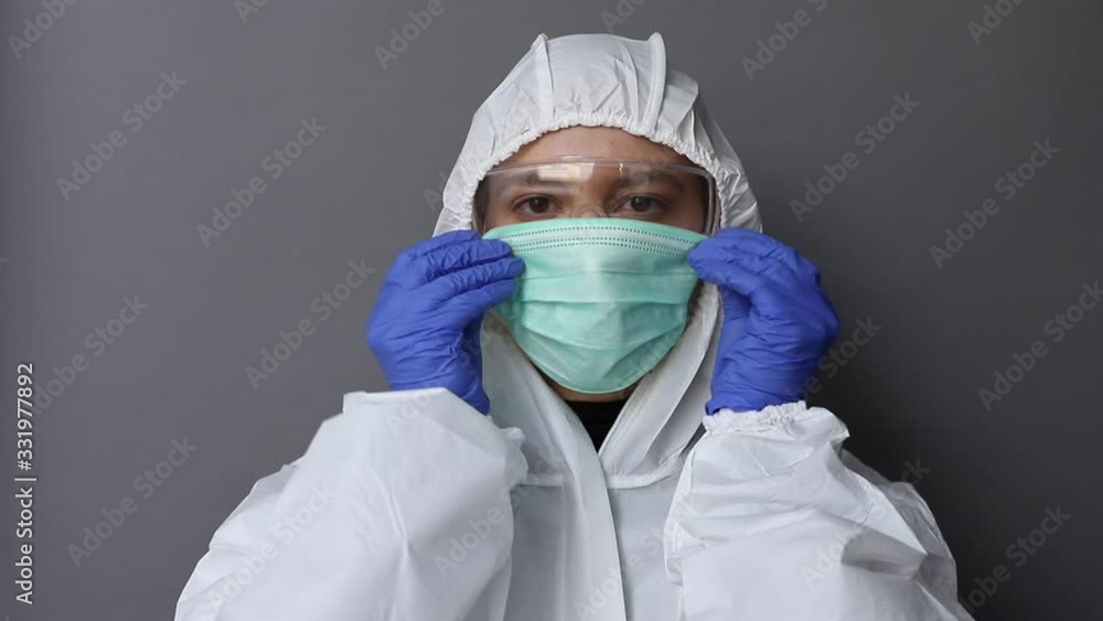 Woman in protective costume puts on a mask Woman in protective costume puts on a mask