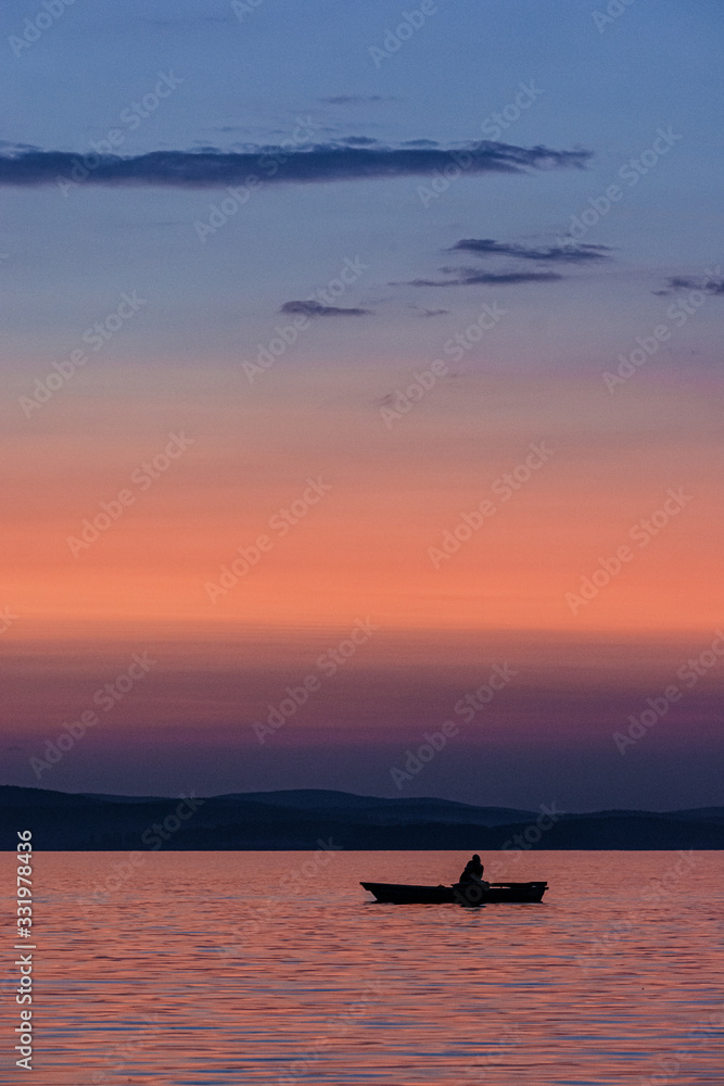 Fototapeta premium Silhouette of a boat on the water during sunset