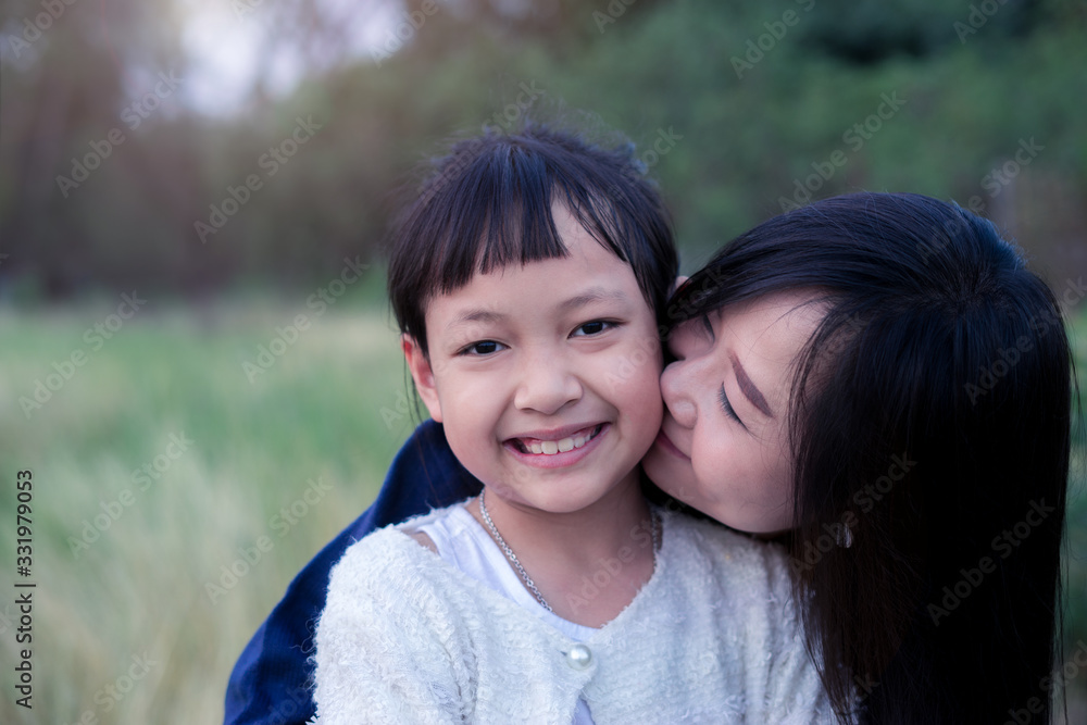 Mother is kissing daughter on summer day.Concept of I love you mom Mother is kissing daughter on summer day.Concept of I love you mom