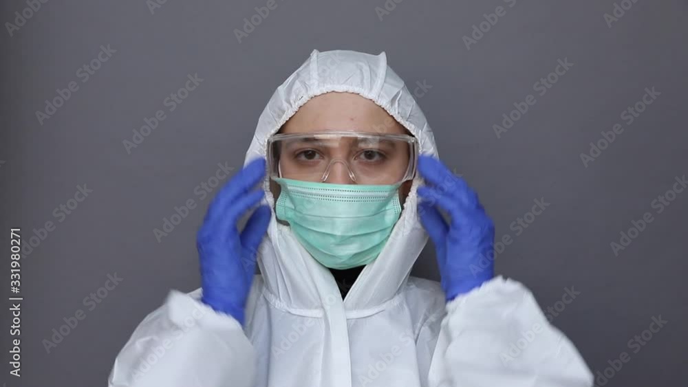 Close up of a woman in protective costume putting on glasses and mask Close up of a woman in protective costume putting on glasses and mask