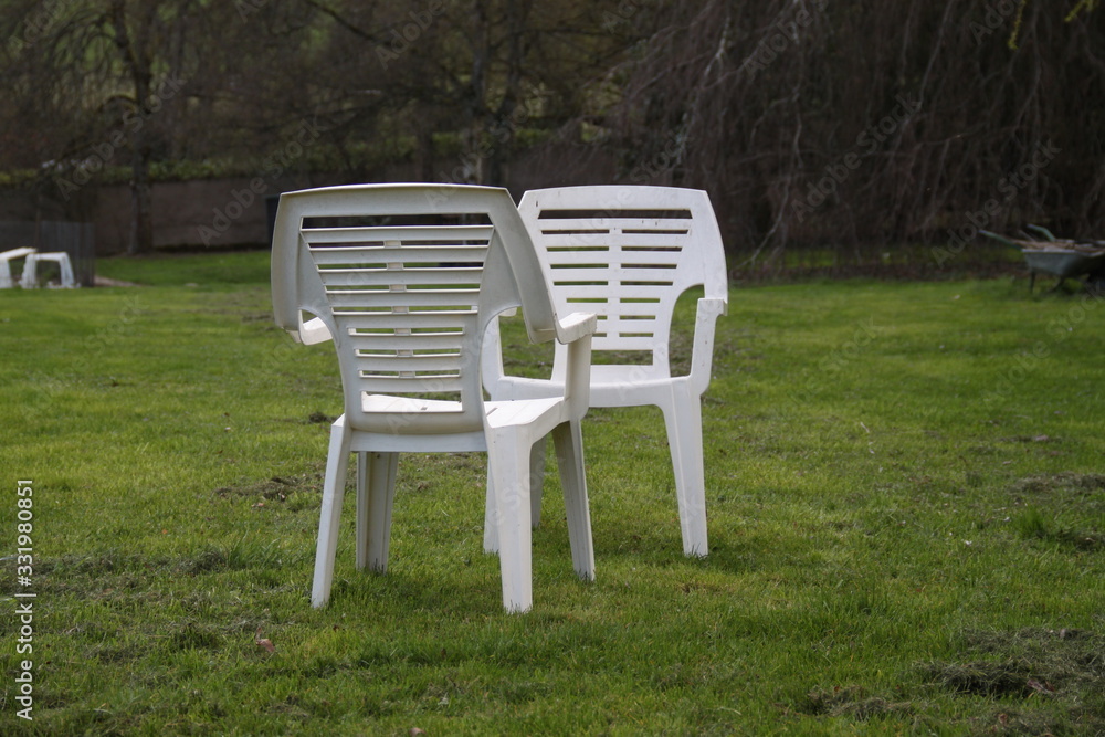 Two white plastic chairs in the garden Two white plastic chairs in the garden