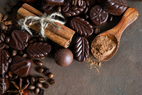 Various types of chocolates and cocoa powder on a brown background. Spices, anise, cinnamon sticks and coffee beans