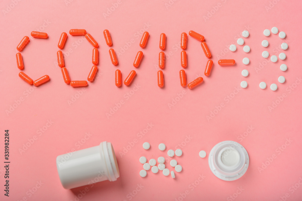 The inscription Covid-19 of tablets, medicines and plastic packaging on a pink background.