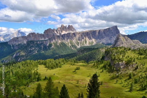 Dolomites mountains  Italy. Sunny day  blue sky  white clouds  green grass. 