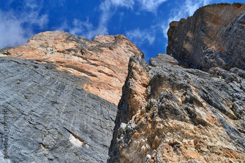 Imposant gray and orange wall of Tofana di Roses. Blue sky, white clouds, Dolomites, Italy. 