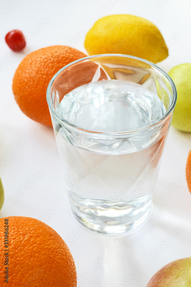 oranges, apples, lemon and a glass of water on a white background oranges, apples, lemon and a glass of water on a white background