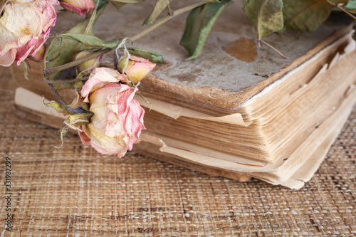 Close up view to old book with dried rose on the top.