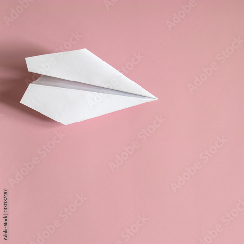 Flat lay white paper plane on pink background.