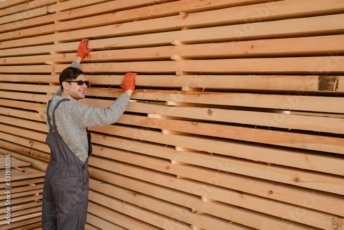 Lateral view of young man carpenter at the wooden warehouse