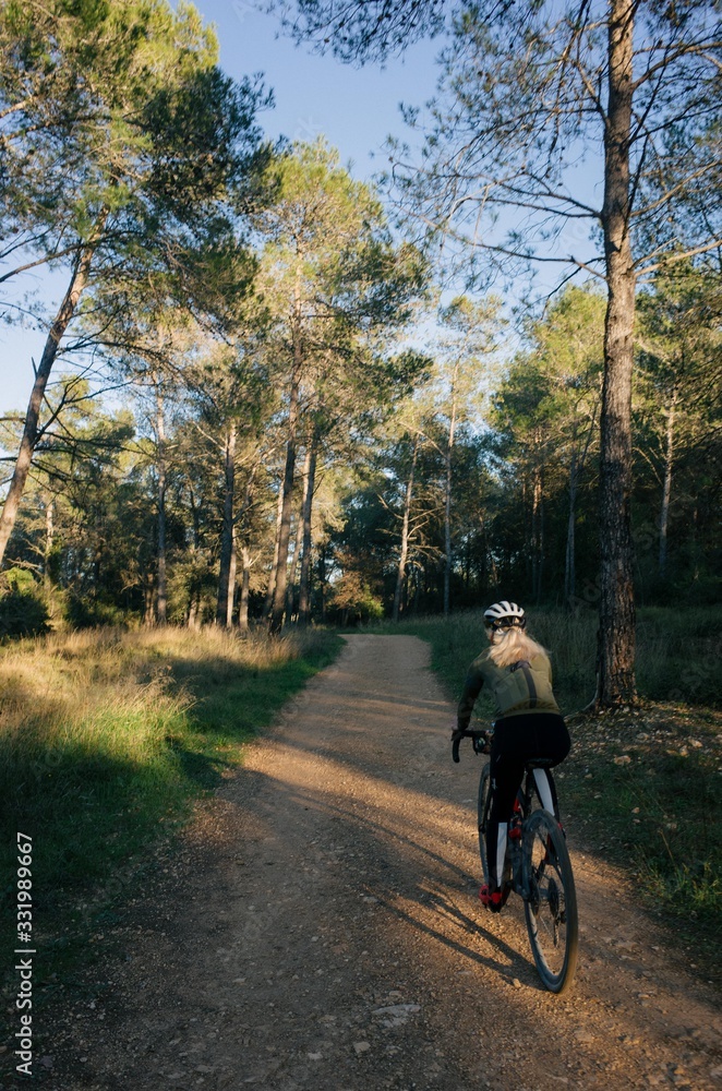 Fototapeta premium Female cyclist riding into the forest