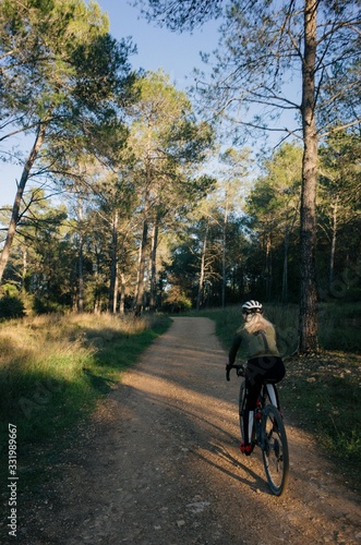 Female cyclist riding into the forest