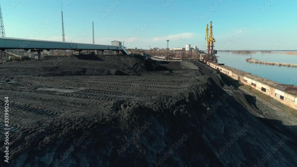 Aerial view of open coal warehouse near river with crane and conveyor Aerial view of open coal warehouse near river with crane and conveyor
