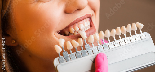 Beautiful blonde patient at the dentist. The young women's teeth being checked, examined and treated by a female dentist with the help of special medical tools