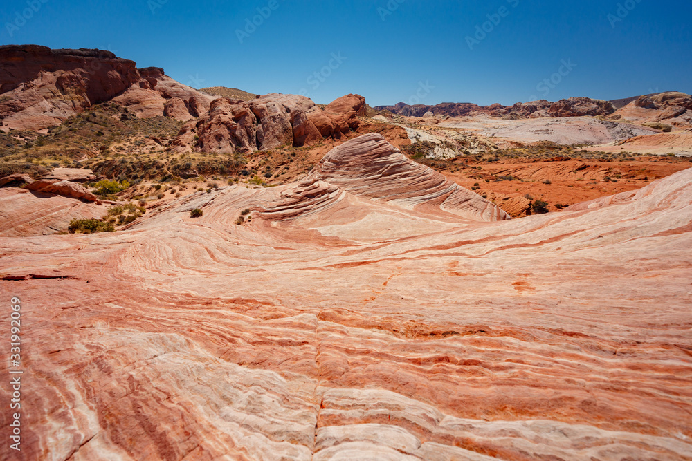 Fire wave with swirly layers of deposited sandstone during wonderful sunny day with blue sky, in Valley of Fire State Park, Nevada, USA Fire wave with swirly layers of deposited sandstone during wonderful sunny day with blue sky, in Valley of Fire State Park, Nevada, USA