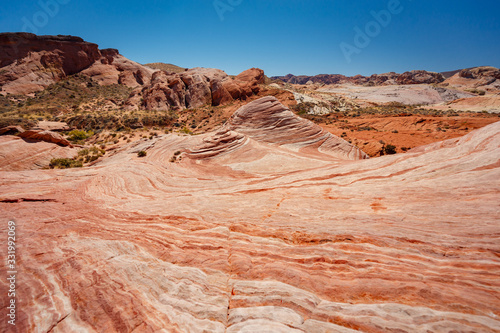 Fire wave with swirly layers of deposited sandstone during wonderful sunny day with blue sky, in Valley of Fire State Park, Nevada, USA