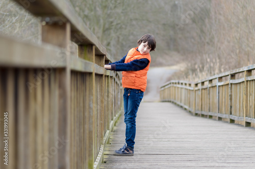 Portrait of a handsome boy standing on a wooden bridge.