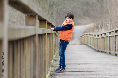 Portrait of a handsome boy standing on a wooden bridge. © Sergey Kohl