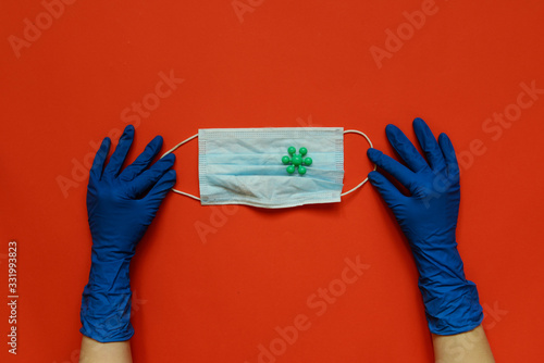 Medical mask in doctors hands with protective gloves. Blue background. Coronavirus concept. Pandemic in the world.