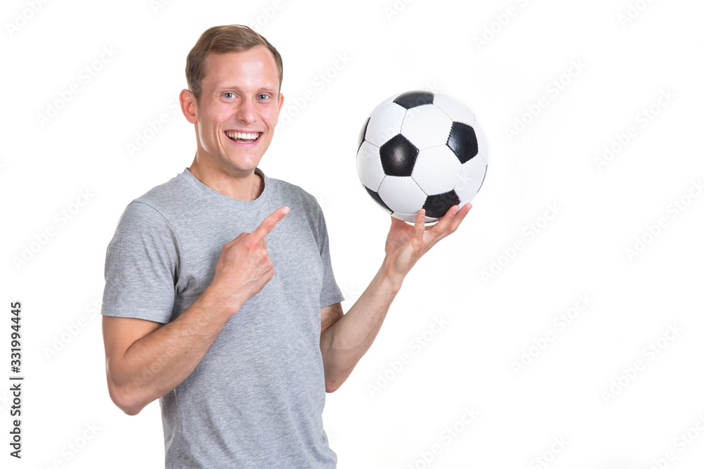 Football coach. Young man points a finger at a soccer ball in his hands, isolated on a white background and looks at the camera. Football coach. Young man points a finger at a soccer ball in his hands, isolated on a white background and looks at the camera.